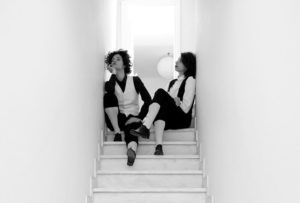 δύο γυναίκες ντυμένες με ανδρικά ρούχα εποχής κάθονται νωχελικά στην κορυφή μίας σκάλας