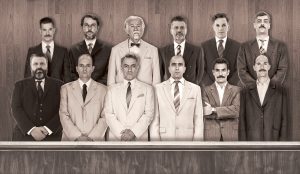 σε μία ασπρόμαυρη φωτογραφία που μοιάζει παλιά 12 άντρες με κοστούμια στέκονται όρθιοι πίσω από το έδρανο των ενόρκων