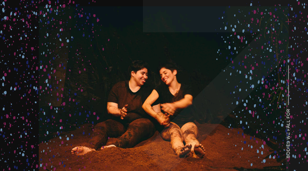 Against a dark, starry backdrop evoking the cosmos—tiny celestial bodies scattered like stardust—a photograph emerges of two women in black, seated side by side atop a thick layer of earth. Their hands are interlaced, their laughter playful, as if caught in a game. Their legs and clothes bear the traces of the soil beneath them.