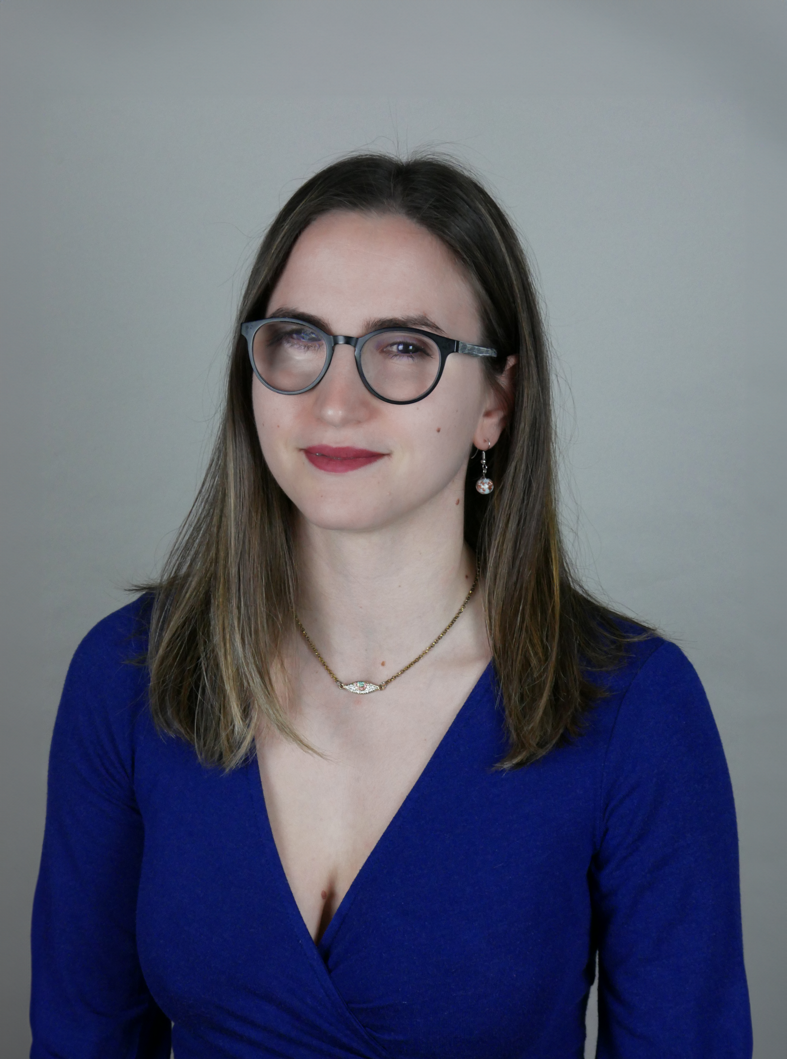 Μια νεαρή γυναίκα με στρογγυλά γυαλιά οράσεως και καστανά ίσια μαλλιά μέχρι τους ώμους ποζάρει κοιτώντας τον φακό με το κεφάλι ελαφρώς γερμένο προς τα δεξιά. Ένα αμυδρό χαμόγελο απλώνεται στα χείλη της. Φορά μπλε μπλούζα με ντεκολτέ και λεπτή αλυσίδα στον λαιμό.